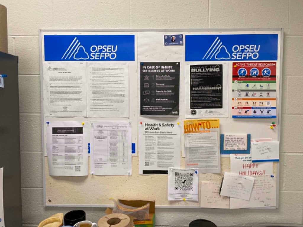 Photograph of a branded union bulletin board with safety posters, LEC list, QR code, and member notes